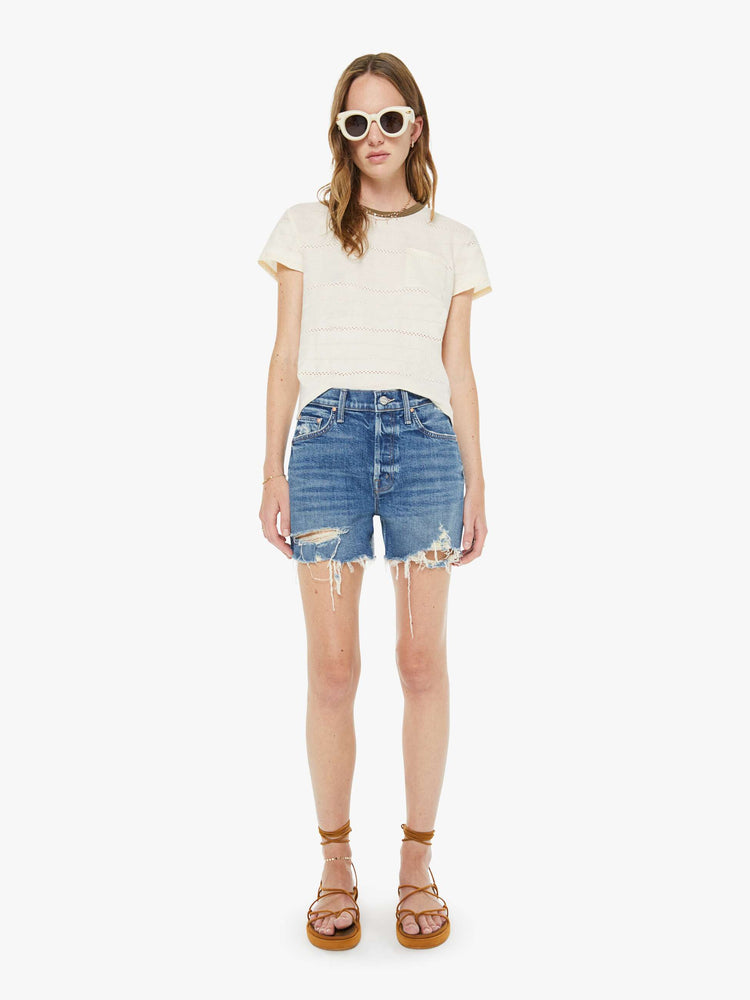 Front view of a woman in a mid blue lived in high-waisted denim shorts with a button fly, 4" inseam and a raw, chewed hem.