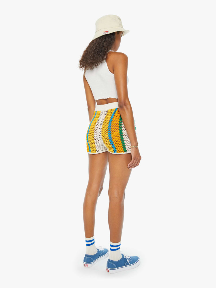 Back view of a woman in cream, orange, green and blue striped crochet shorts featuring delicate openwork details.