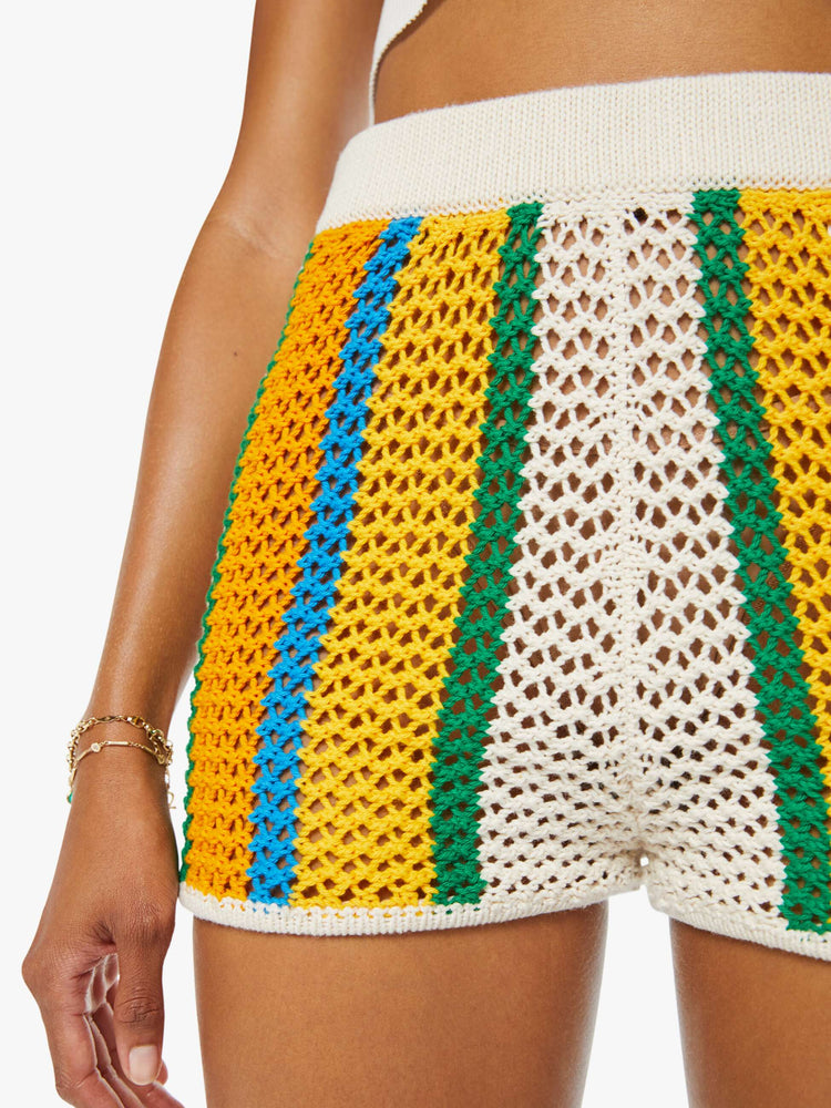 Detailed front view of a woman in cream, orange, green and blue striped crochet shorts featuring delicate openwork details.