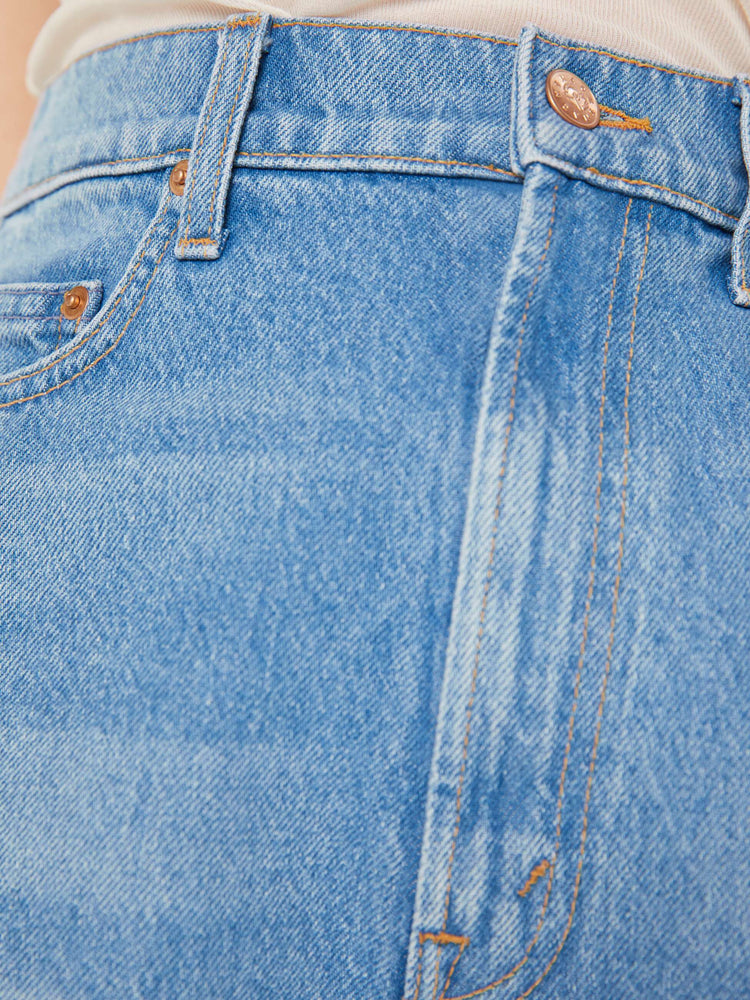 Close up detail view of a light blue denim short.