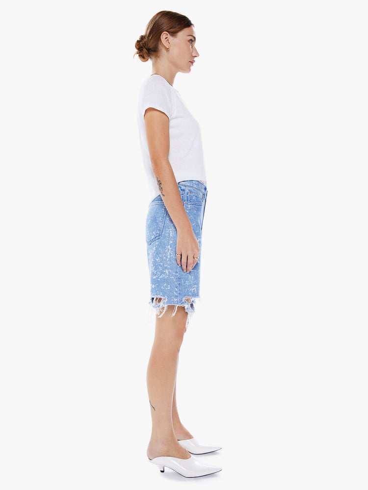 Side view of a woman's bermuda high rise, 9-inch inseam, wide leg and frayed hem in a light blue wash with bleach details.