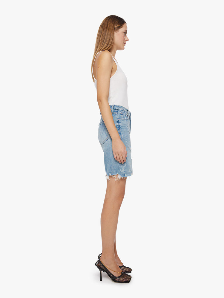 Side view of a woman light blue wash with bleach splatters bermuda short features a high rise, 9.25-inch inseam, wide leg and frayed hem.