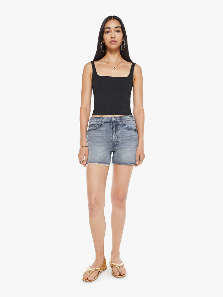 Front view of a woman in a light grey high-waisted denim shorts with a button fly, frayed hem and vintage-inspired fit.