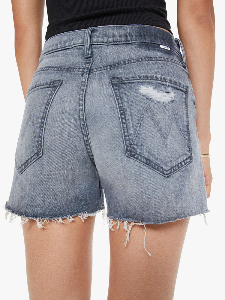 Back close uo view of a woman in a light grey high-waisted denim shorts with a button fly, frayed hem and vintage-inspired fit.