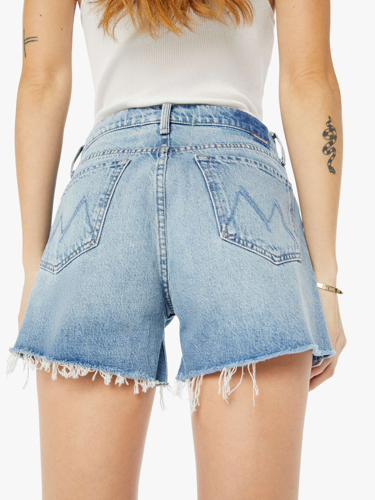 Back close up view of a womens light blue wash denim short featuring a high rise and frayed hem.