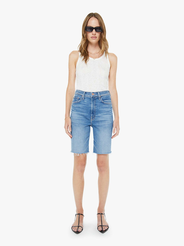 Front view of a woman in a high-waisted denim shorts with a straight leg, zip fly, 9-inch inseam and a frayed hem.
