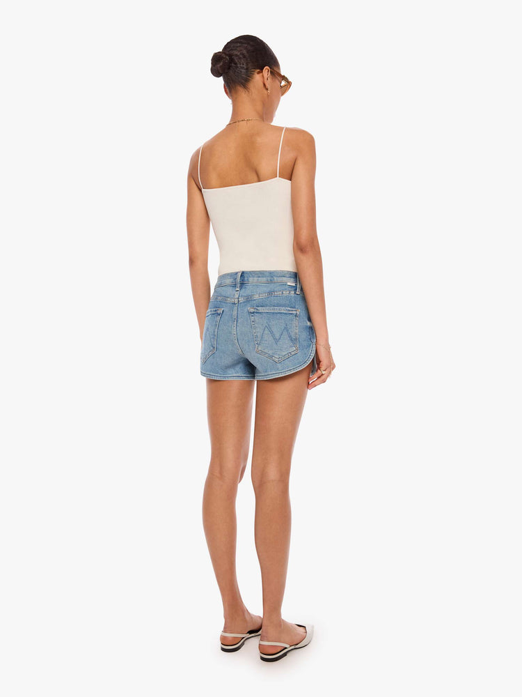 Back view of a woman in a light blue high-waisted jean shorts with a button fly and a curved, clean hem. 