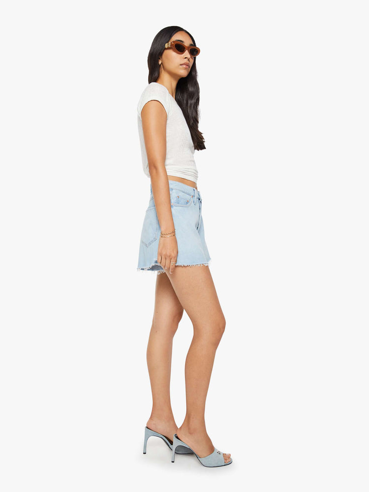 Side view of a woman in a super high-waisted denim shorts with a button fly, 3.25-inch inseam and a wide leg opening that flares out.