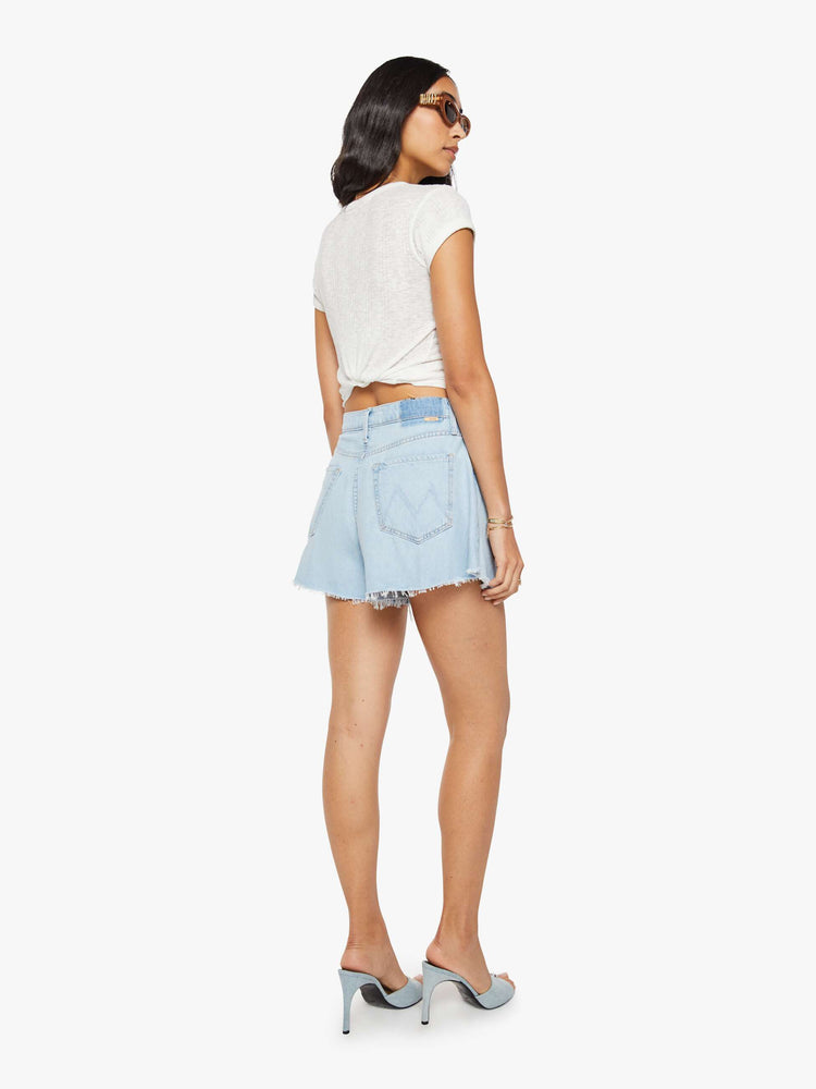 Back view of a woman in a super high-waisted denim shorts with a button fly, 3.25-inch inseam and a wide leg opening that flares out.