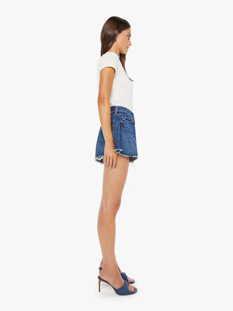 Side view of a woman in a super high-waisted denim shorts with a button fly, 3.25-inch inseam and a wide leg opening that flares out.