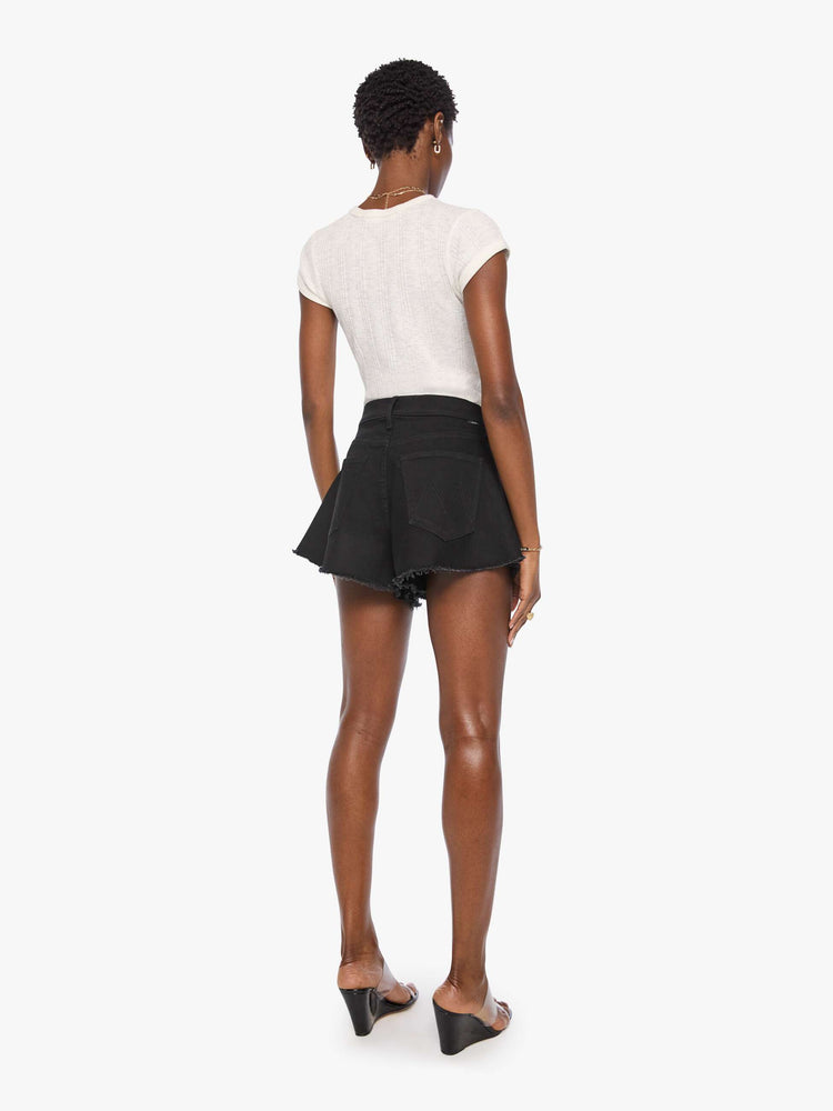 Back view of a woman in a black super high-waisted denim shorts with a button fly, 3.25-inch inseam and a wide leg opening that flares out.