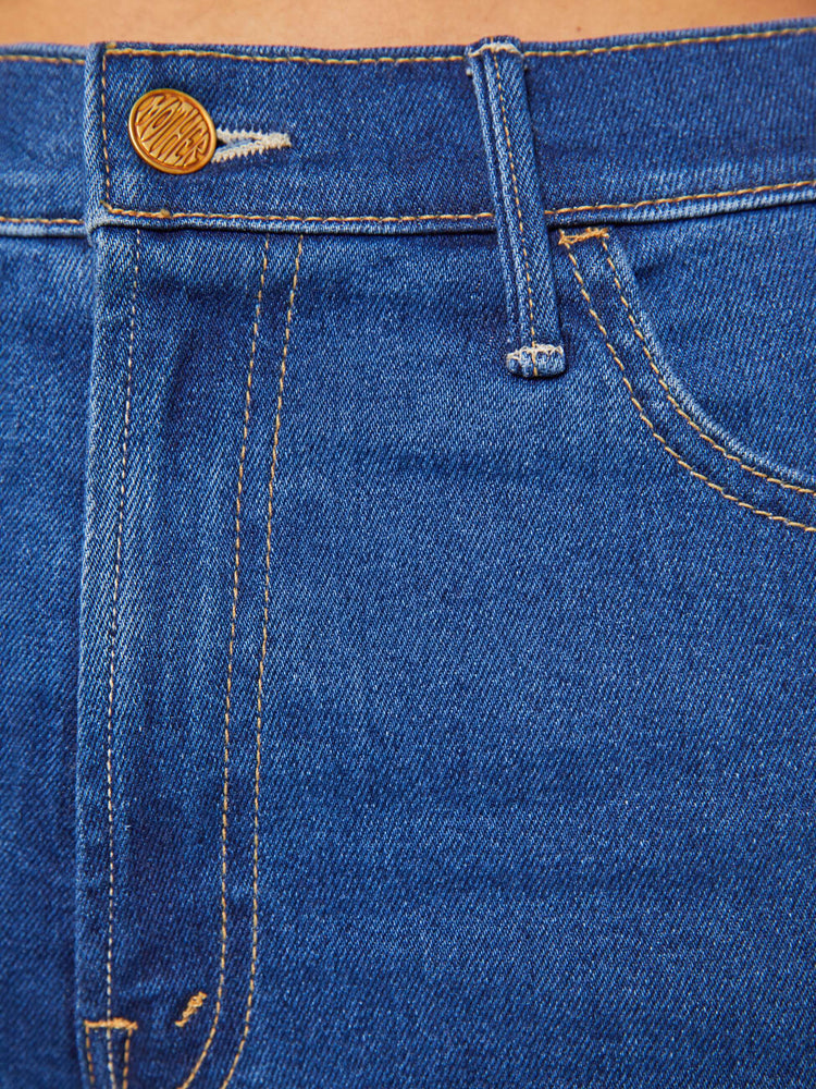 Swatch view of a woman in a  midblue high-waisted denim shorts with a zip fly, short inseam and frayed hem.