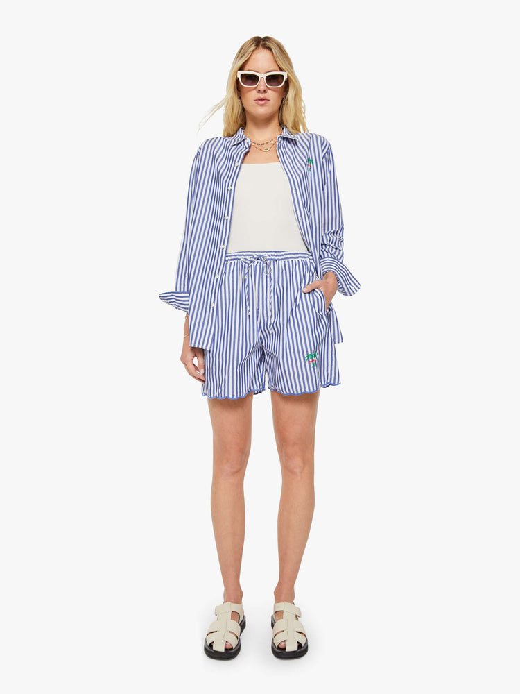 Front view of a woman in shorts with blue and white stripes with MOTHER's name embroidered with two small palm trees at the hem.