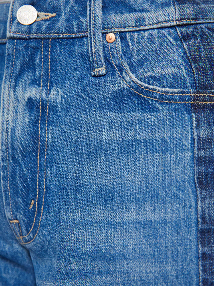 Swatch view of a woman in mid-blue with whiskering, fading and darker denim panels on the outer seams bermuda shorts with a mid rise, loose, wide leg, zip fly and a knee-length inseam with a frayed hem.