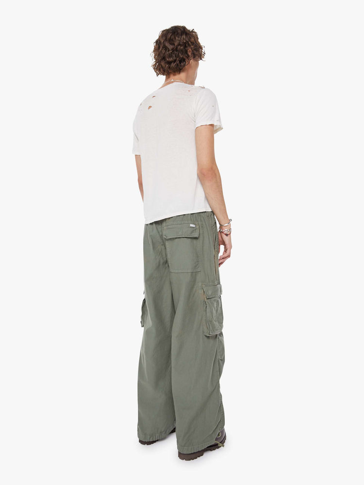 Back  view of a man in an army green military-inspired pants with a loose leg, slightly dropped crotch, oversized cargo pockets, a 26.5-inch inseam and drawstring hems.