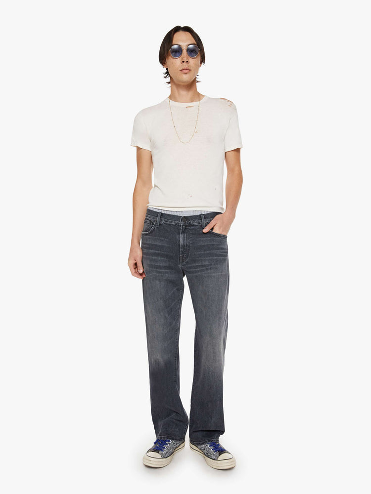 Front view of a man in faded black loose-fitting jean with a mid rise, zip fly, 31-inch inseam and a clean hem.