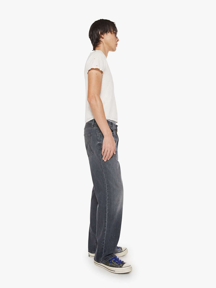 Side view of a man in faded black loose-fitting jean with a mid rise, zip fly, 31-inch inseam and a clean hem.