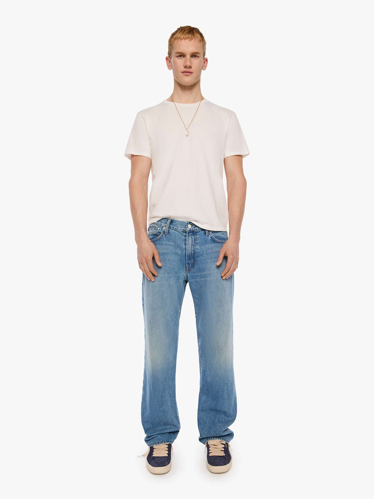 Front view of a man in light blue loose-fitting jean with a mid rise, zip fly, 31-inch inseam and a clean hem.