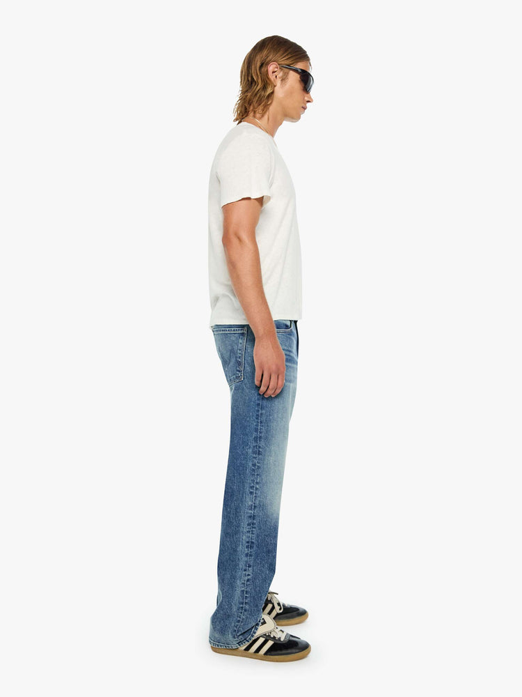 Side view of a woman in a loose-fitting jean with a mid rise, zip fly, 31-inch inseam and a clean hem.
