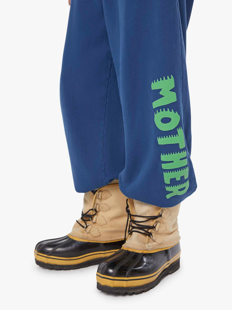 Close up view of a man in blue sweatpants with an elastic waistband and hems, slit and patch pockets and a loose, comfortable fit. 