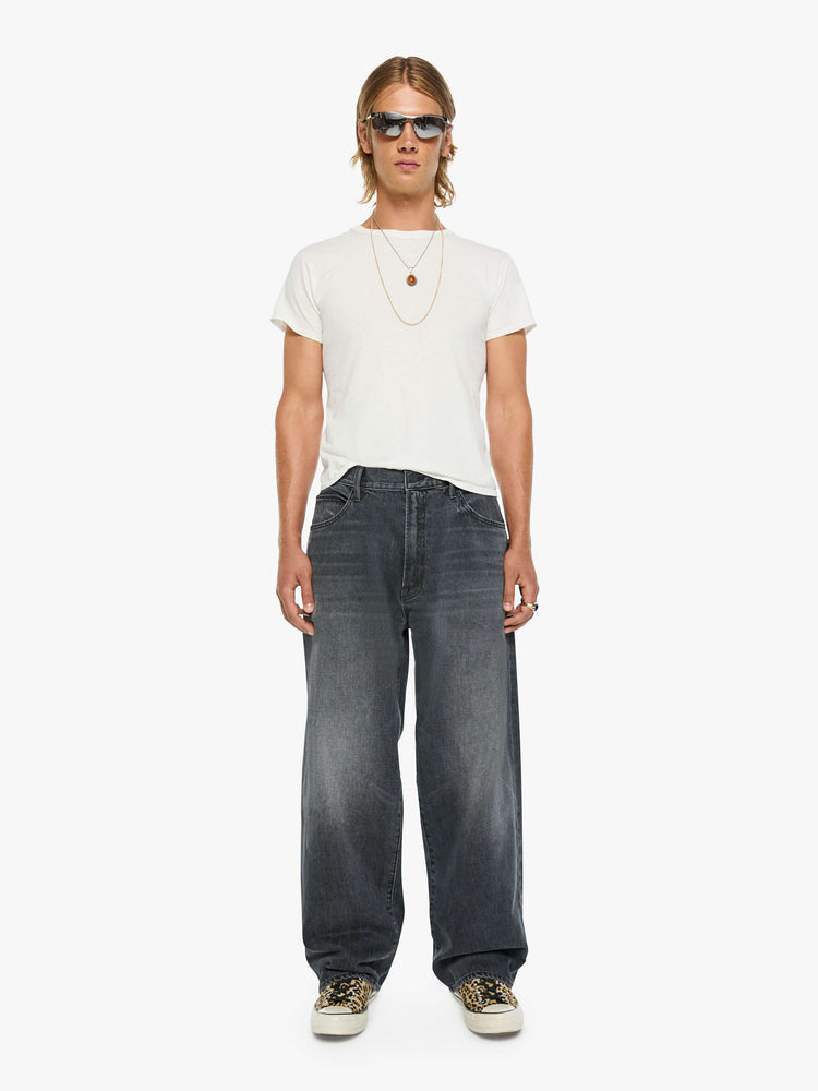 Front view of a man in dark grey baggy jean with a high rise, zip fly, 30-inch inseam and a clean hem.