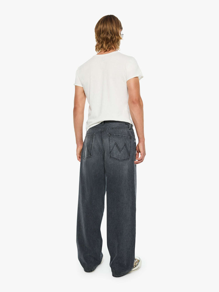 Back view of a man in dark grey baggy jean with a high rise, zip fly, 30-inch inseam and a clean hem.