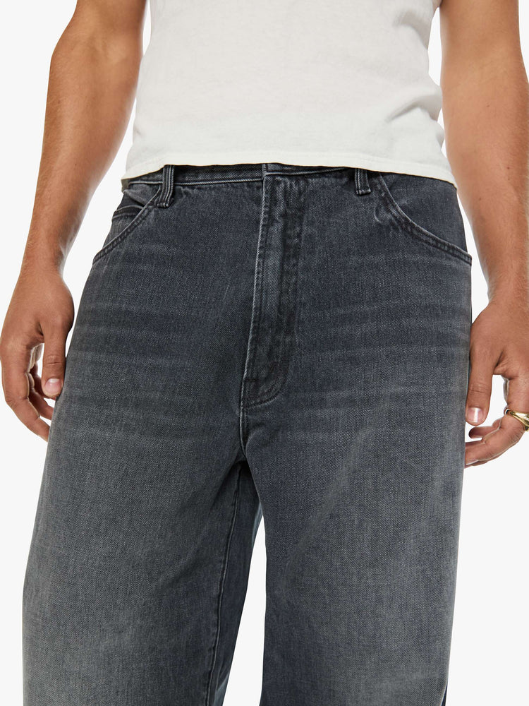 Close up view of a man in dark grey baggy jean with a high rise, zip fly, 30-inch inseam and a clean hem.