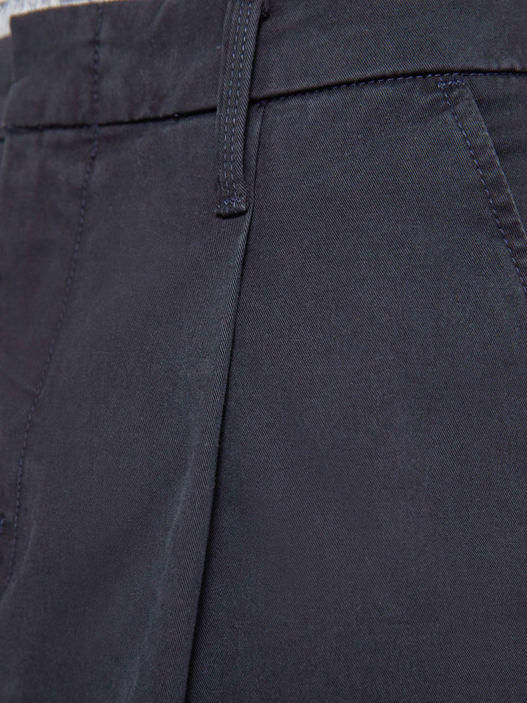 Swatch view of a man in a navy relaxed pants with a mid rise, pleats at the waistband, a zip fly, slit pockets and a 31-inch inseam with a clean hem.