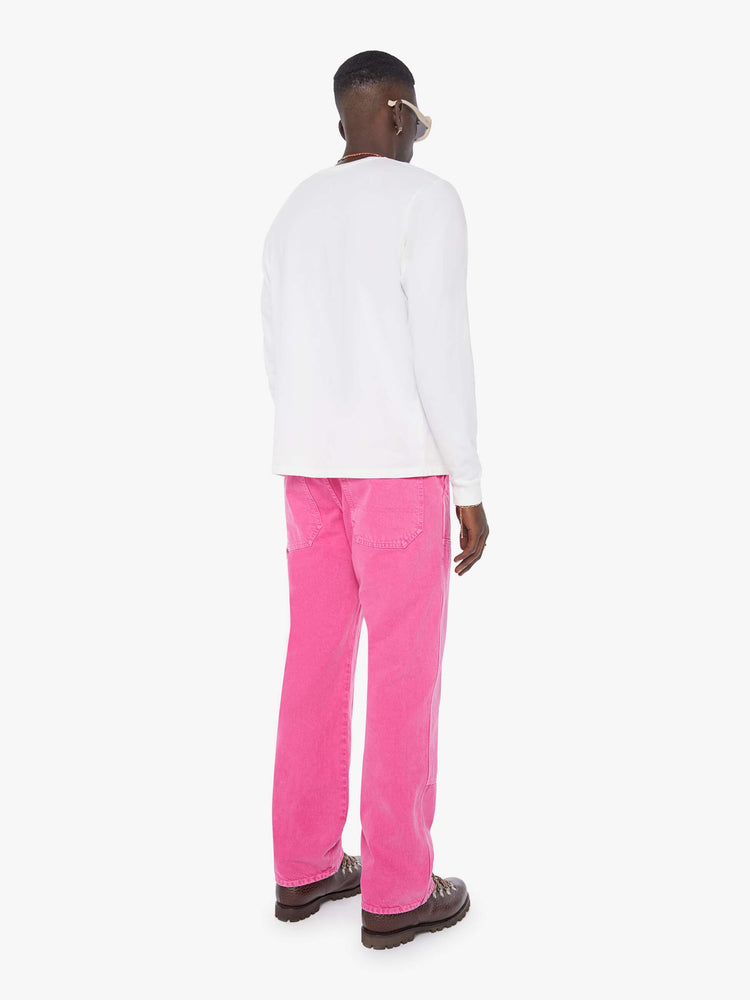 Back view of a man in hot pink loose-fitting jean with a mid rise, zip fly, hammer loop, 31-inch inseam and a clean hem.