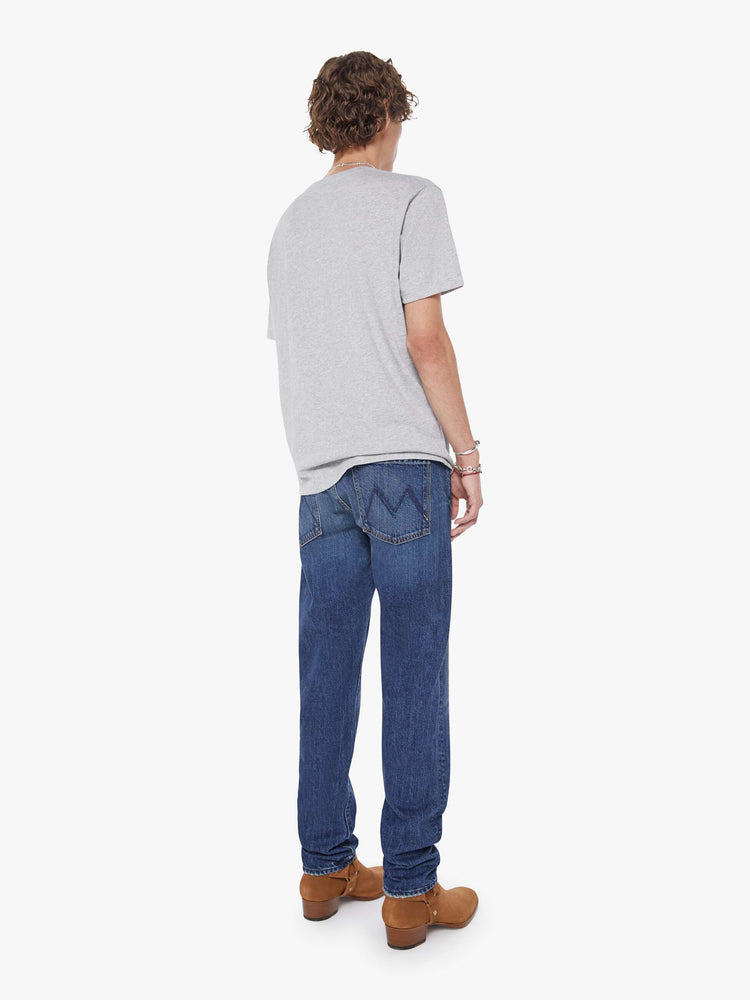 Back view of a man in a mid-blue slim-straight leg with a mid rise, button fly, 32-inch inseam and a clean hem.