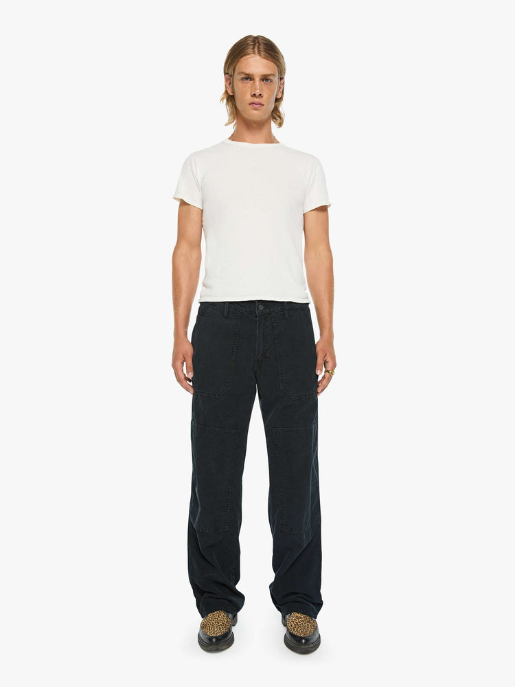 Front view of a man in a corduroy pant with a loose straight leg, patch pockets, a zipper pocket along the outer seam, patches on the knees, a hammer loop, zip fly and a 32-inch inseam with a clean hem.