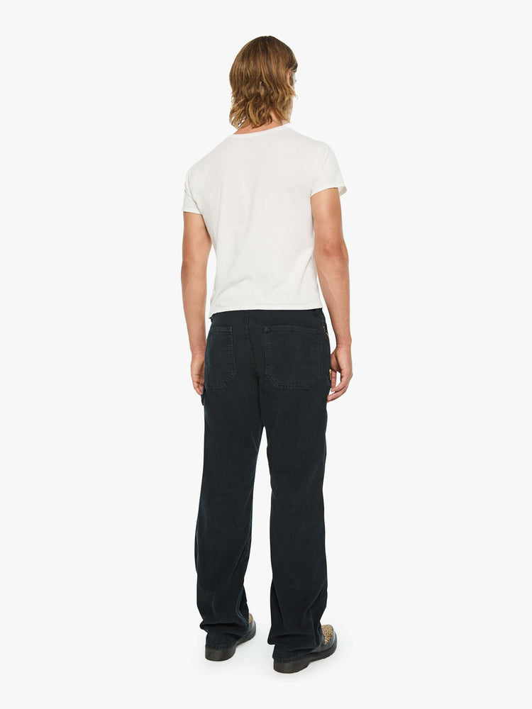 Back  view of a man in a corduroy pant with a loose straight leg, patch pockets, a zipper pocket along the outer seam, patches on the knees, a hammer loop, zip fly and a 32-inch inseam with a clean hem.