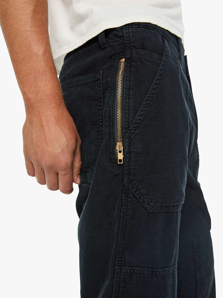 Zip close up  view of a man in a corduroy pant with a loose straight leg, patch pockets, a zipper pocket along the outer seam, patches on the knees, a hammer loop, zip fly and a 32-inch inseam with a clean hem.