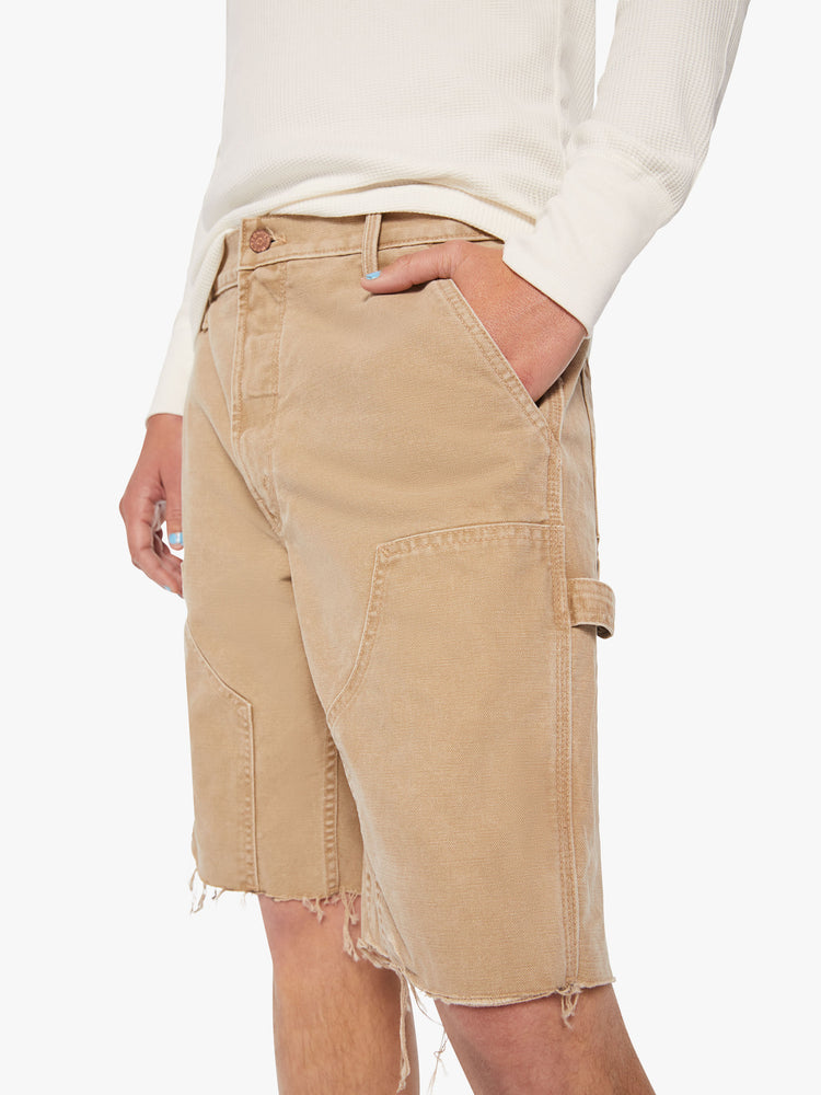 Close up view of a men cut-off knee patches shorts are designed in a khaki hue.