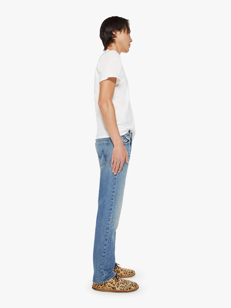 Side view of a woman in a light blue classic straight leg with a mid rise, button fly, 32-inch inseam and a clean hem.