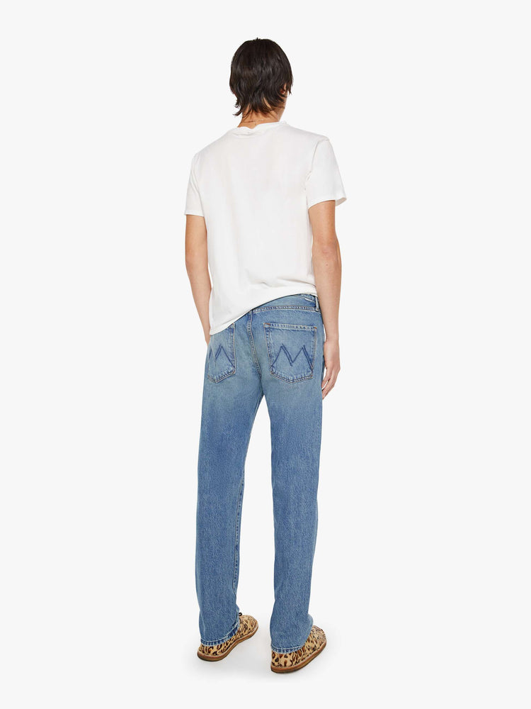 Back view of a woman in a light blue classic straight leg with a mid rise, button fly, 32-inch inseam and a clean hem.