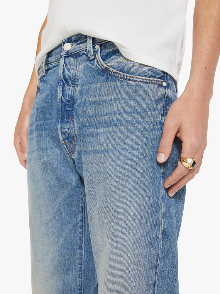 Close up view of a woman in a light blue classic straight leg with a mid rise, button fly, 32-inch inseam and a clean hem.