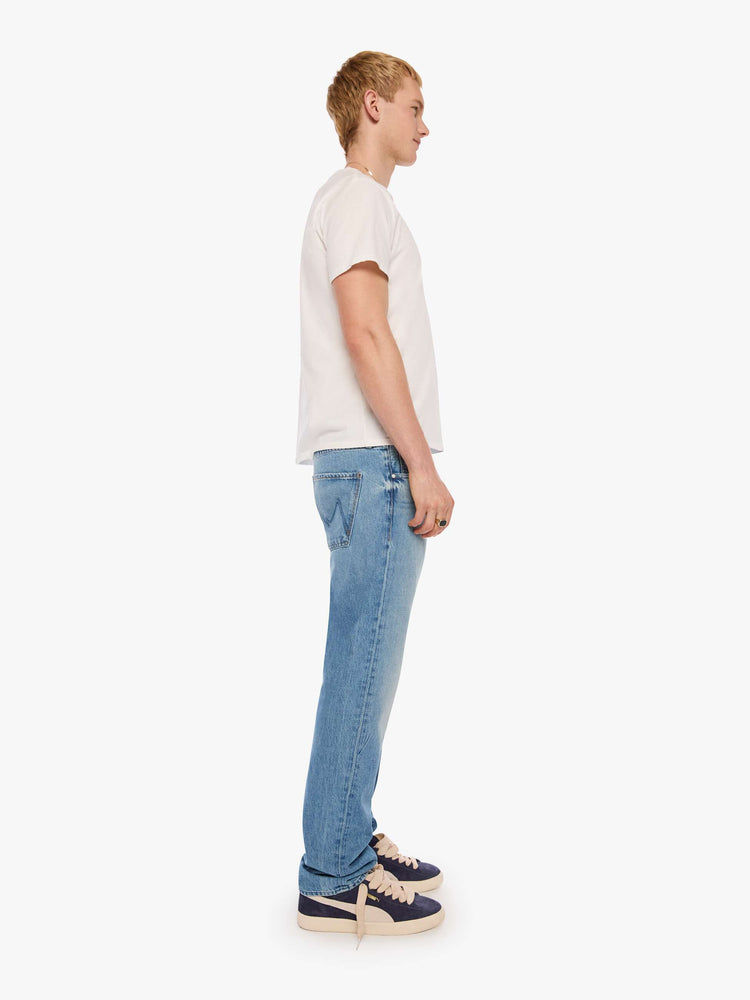 Side view of a man in light blue classic straight leg with a mid rise, button fly, 32-inch inseam and a clean hem.
