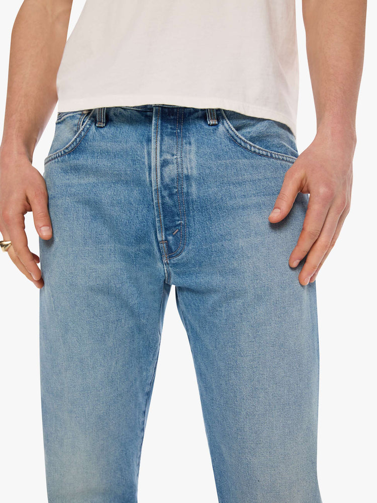 Close up view of a man in light blue classic straight leg with a mid rise, button fly, 32-inch inseam and a clean hem.