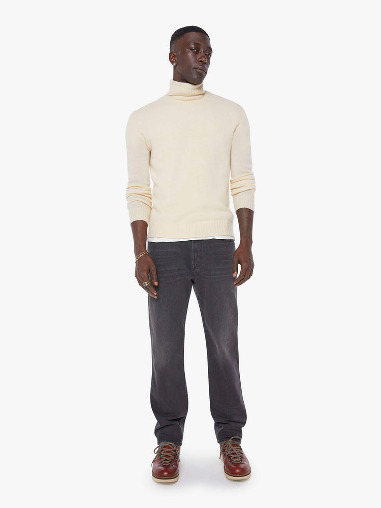 Front view of a man in a dark grey straight-leg jean with a mid rise, zip fly, 30-inch inseam and a clean hem. 