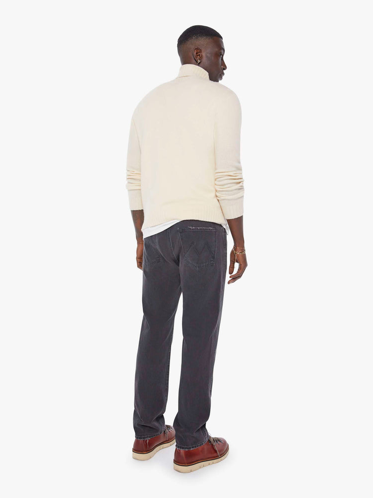 Back view of a man in a dark grey straight-leg jean with a mid rise, zip fly, 30-inch inseam and a clean hem. 