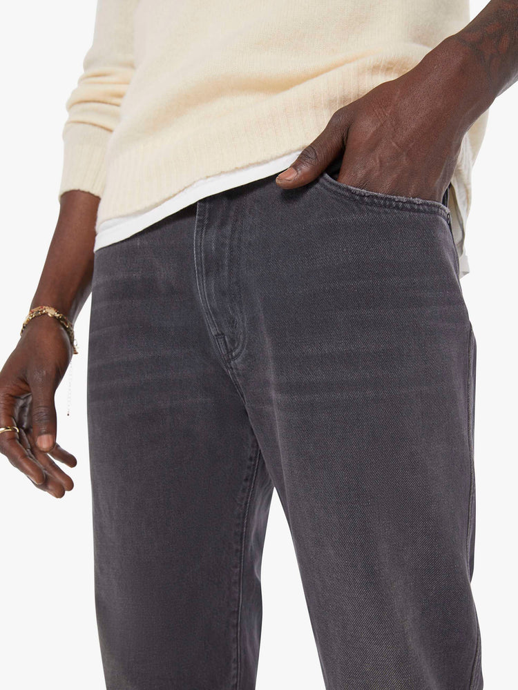 Close up view of a man in a dark grey straight-leg jean with a mid rise, zip fly, 30-inch inseam and a clean hem. 
