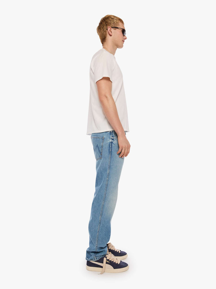 Side view of a man in a light blue straight-leg jean with a mid rise, zip fly, 30-inch inseam and a clean hem.