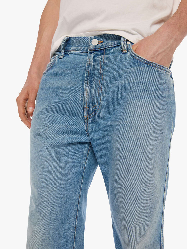 Close up view of a man in a light blue straight-leg jean with a mid rise, zip fly, 30-inch inseam and a clean hem.