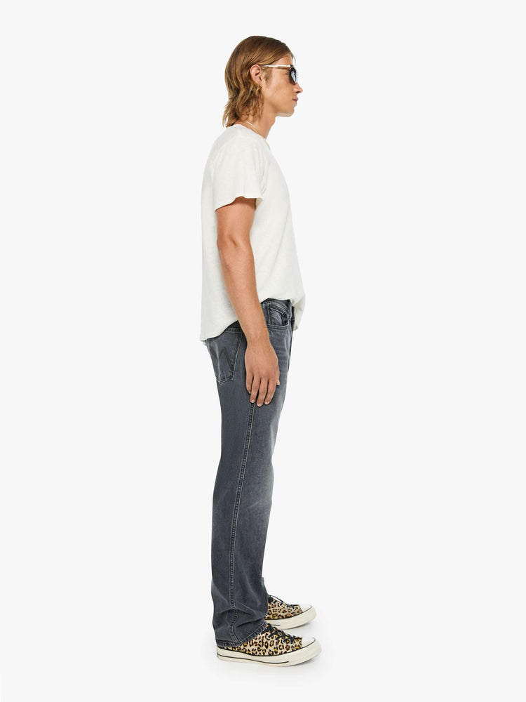 Side view of a man in a dark grey straight-leg jean with a mid rise, zip fly, 31-inch inseam and a clean hem.