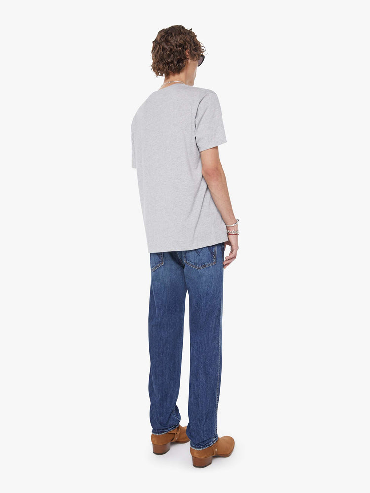 Back view of a man in a mid-blue straight-leg jean with a mid rise, zip fly, 30-inch inseam and a clean hem.