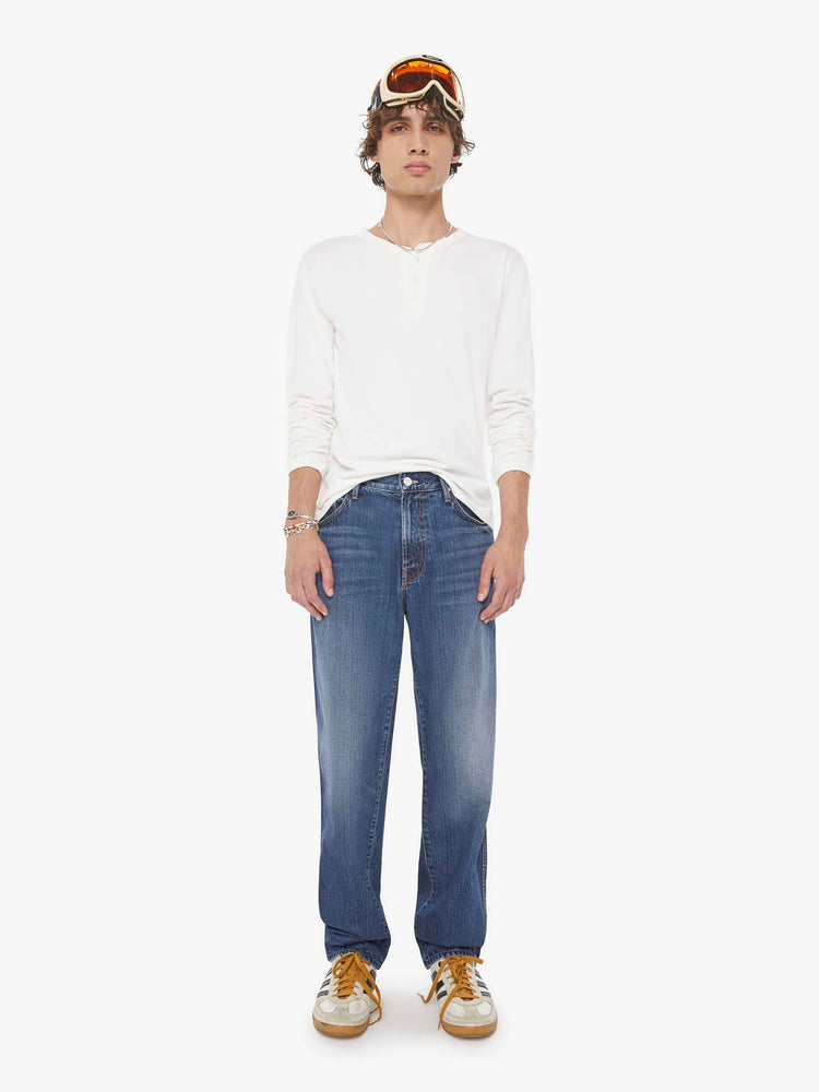 Front view of a woman in a med blue straight-leg jean with a mid rise, zip fly, 30-inch inseam and a clean hem.
