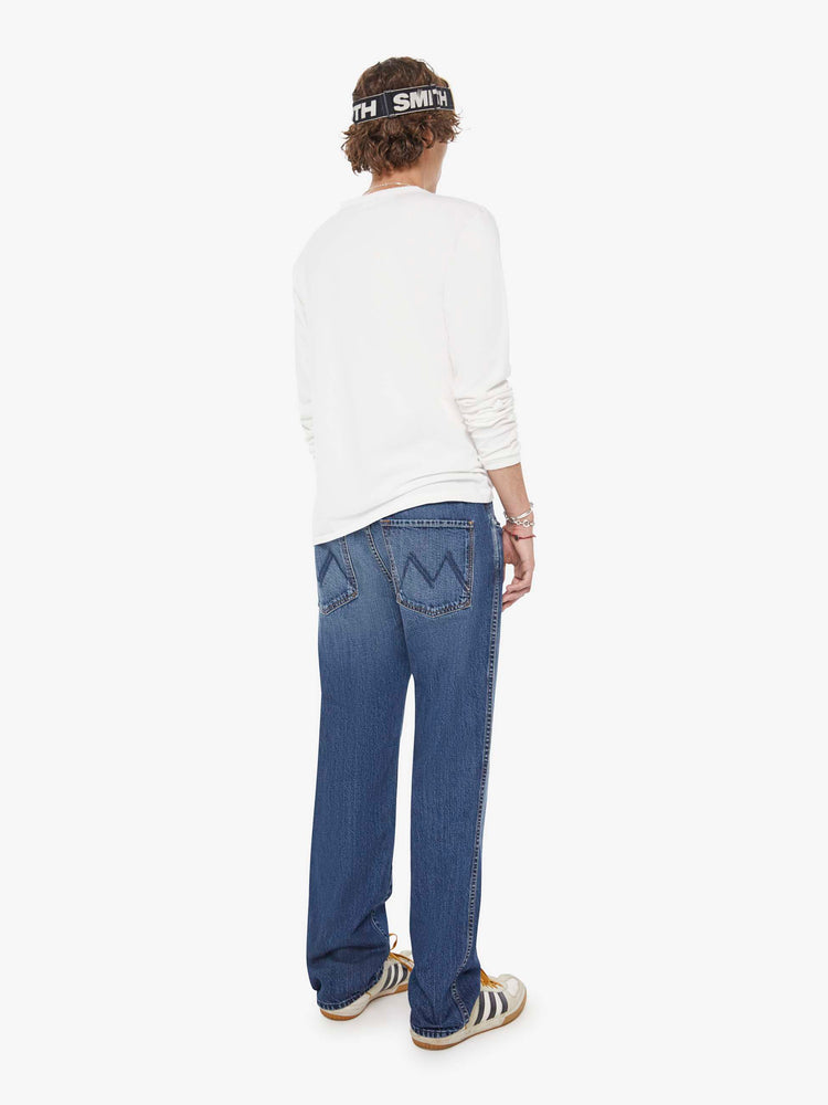 Back view of a woman in a med blue straight-leg jean with a mid rise, zip fly, 30-inch inseam and a clean hem.