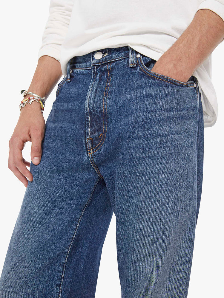 Close up view of a woman in a med blue straight-leg jean with a mid rise, zip fly, 30-inch inseam and a clean hem.