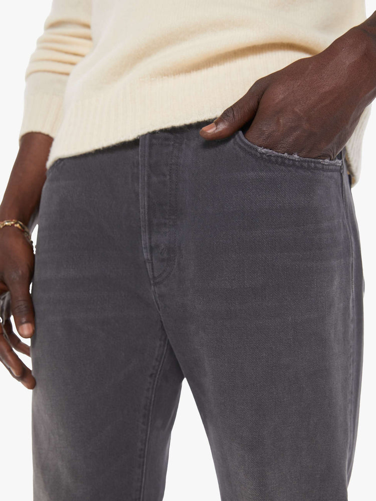 Close up view of a man in a dark grey  standard straight leg with a mid rise, button fly and 32-inch inseam with a clean hem. 